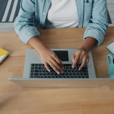 Person typing on a laptop at a wooden desk.